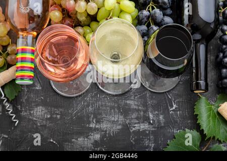 Degustationsverkostung nach Wahl des Weins. Weißwein Rosérot Sorten Wein in Gläsern und Flaschen. Verschiedene Sorten Trauben. Weinkomposition mit auf dunkel Stockfoto