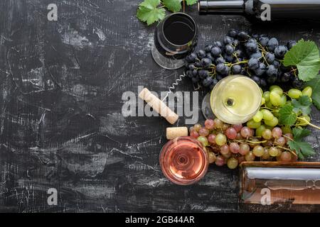 Weißwein Rose und Rotwein in Gläsern. Weinsorten in Flaschen. Verschiedene Sorten Trauben rosa schwarz grün. Weinzusammensetzung mit Korkenzieher Stockfoto