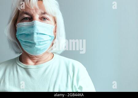 Porträt der kaukasischen Frau in einer medizinischen Maske isoliert auf einem grauen Wand Hintergrund. Stockfoto