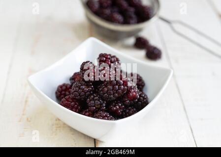 Eine Schüssel mit frisch gepflückten Boysenbeeren auf einem weißen Tisch. Stockfoto