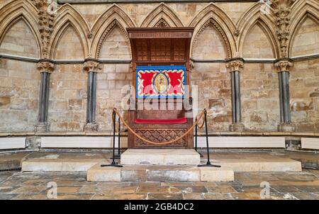 Ein festlicher Stuhl aus Holz (mit buntem Wandteppich von Maria und Jesus) im Kapitelhaus der Kathedrale in Lincoln, England. Stockfoto