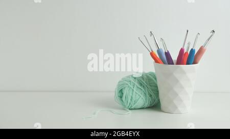 Bunte Häkelnadeln in weißem Becher. Weißer Hintergrund. Speicherplatz kopieren Stockfoto