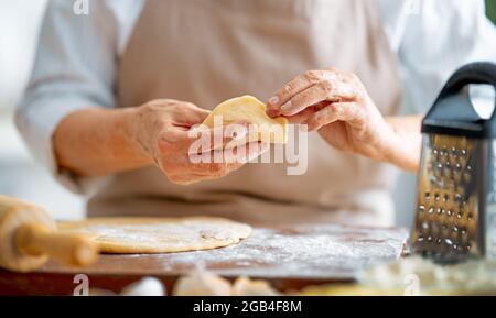 Nahaufnahme des Bäckers funktioniert. Hausgemachtes Brot. Hände, die Teig auf Holztisch vorbereiten. Stockfoto