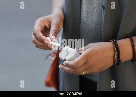 Nahaufnahme einer afrikanischen Frau, die die kabellosen Kopfhörer aus der Verpackung nimmt Stockfoto