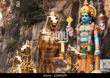 Vier goldene Pferde vor einer großen Statue von lord krishna am Eingang der ramayana-Höhle im malerischen Gebiet der Batu-Höhle Gombak, Selangor Malay Stockfoto