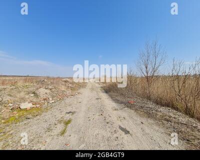 Leere, gerade unbefestigte Landstraße führt zum Horizont Stockfoto