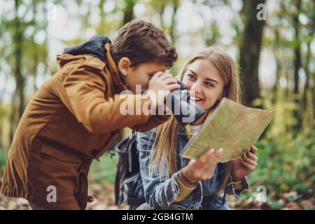 Glückliche Mutter und Sohn wandern im Wald. Junge beobachtet die Natur mit einem Fernglas. Stockfoto