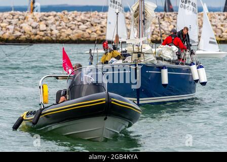 Chase Boot Rib eskortiert eine Rennyacht in den Hafen von cowes auf der Insel wight während der cowes Week Segelregatta für Yachten Stockfoto