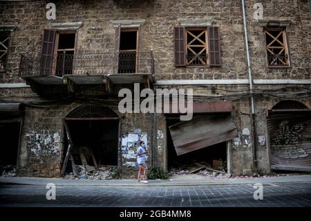 Beirut, Libanon. Juli 2021. Ein Bild, das am 2. August 2021 zur Verfügung gestellt wurde, zeigt eine Frau, die fast ein Jahr nach der massiven Hafenexplosion in Beirut im August 2020 an einem verwüsteten Gebäude im Gemmayzeh-Gebiet vorbeigeht. Am 04. August 2020 ging eine große Menge Ammoniumnitrat, die im Hafen von Beirut gelagert wurde, los, wobei mindestens 218 Menschen getötet und 7,500 weitere verletzt wurden. Quelle: Marwan Naamani/dpa/Alamy Live News Stockfoto