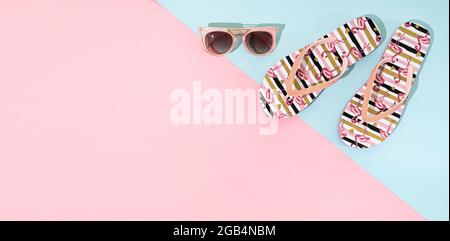 Eine Pare von Sommer-Sandalen, Flip Flop und rosa Sonnenbrille auf rosa und blauen Hintergrund, Draufsicht, Copy Space Stockfoto