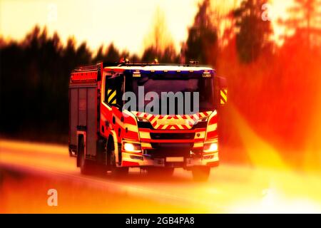 Scania Feuerwehrauto mit Geschwindigkeit auf der Autobahn, umgeben von Flammen, um das Rettungskonzept. Illustratives Editorial-Bild. Stockfoto