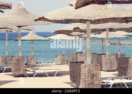 Schöner Strand. Sonnenliegen und Sonnenschirme am Sandstrand am Meer. Sommerferien und das Konzept der Erholung für den Tourismus. Tropische Landschaft Stockfoto