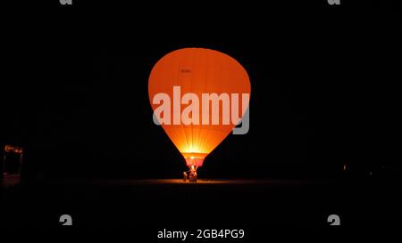 Thiene, Italien, 8. JULI 2021, Heißluftballon beleuchtet von der Gasflamme in der Nacht. Ballons Libert L 3400 Stockfoto