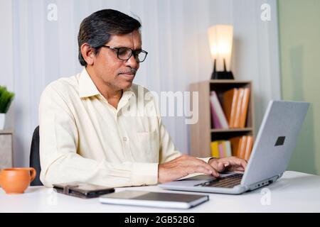 Lächelnder Geschäftsmann beim Arbeiten oder Chatten auf dem Laptop im Büro - Konzept der Nutzung von Technologie, Kommunikation und Internet Stockfoto