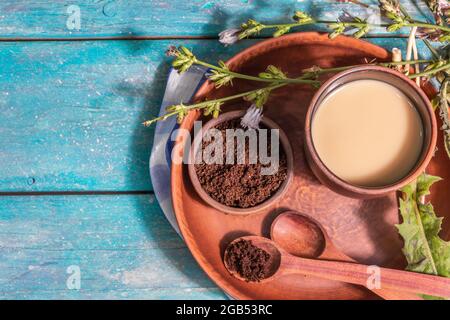 Natürlicher Zichorien-Kaffee mit frischen Blumen und Pulver. Koffeinfreies Getränk in einem Keramikglas. Alternative Ersatz für Kaffee, Koffein. Türkis Stockfoto