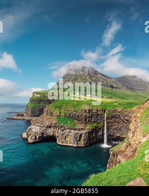 Unglaublicher Tagesblick auf den Wasserfall Mulafossur im Dorf Gasadalur, Insel Vagar auf den Färöern, Dänemark. Landschaftsfotografie Stockfoto