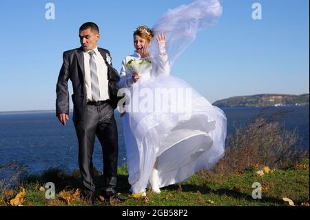 Das Brautpaar, das vor einem Fluss posierte, wandte sich in äußerster Abscheu von der glücklich lächelnden Braut ab. 23. Juli 2011. Kiew, Ukraine Stockfoto