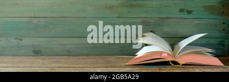 Öffnen Sie ein Vintage-Buch auf grünem Hintergrund. Lesen, Literatur, Bildung, Bibliothek, Home Office, Back-to-School-Konzept, Panorama, Kopierraum Stockfoto