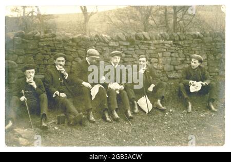 Originalpostkarte aus dem frühen 20. Jahrhundert mit jungen Männern, die auf einem Streifzug zu Mittag essen, um 1920 in Großbritannien Stockfoto