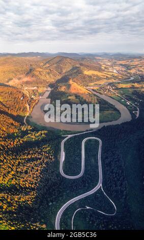 Antenne drone Blick über den Herbst in den Bergen mit Mountain Road Serpentine, Fluss und Wald. Landschaftsfotografie Stockfoto