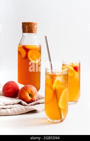 Zwei Gläser und eine Kanne hausgemachten kalten Pfirsich-Eistee. Stockfoto