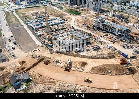 Luftpanorama der großen Baustelle an sonnigen Sommertag. Bau von neuen Gebäuden und Stadtstraße. Stockfoto