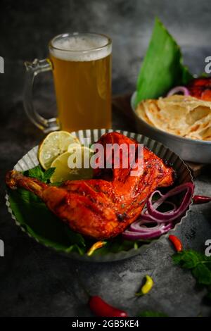 Hausgemachte Tandoori-Hähnchenschenkelstücke, serviert auf einem Teller mit Roti Paratha und Reis – indisches Speisekonzept Stockfoto