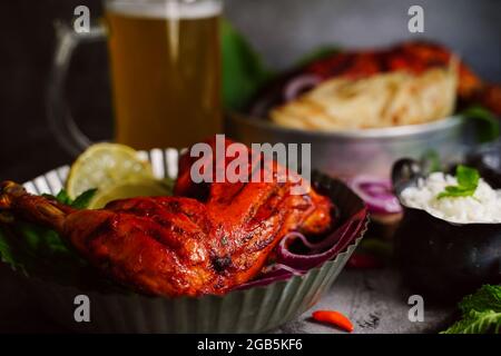 Hausgemachte Tandoori-Hähnchenschenkelstücke, serviert auf einem Teller mit Roti Paratha und Reis – indisches Speisekonzept Stockfoto