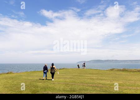 Menschen, die im Sommer auf dem Küstenpfad der Isle of Anglesey in der Red Wharf Bay auf dem Küstenpfad der Isle of Anglesey wandern, Anglesey, Wales, Großbritannien Stockfoto