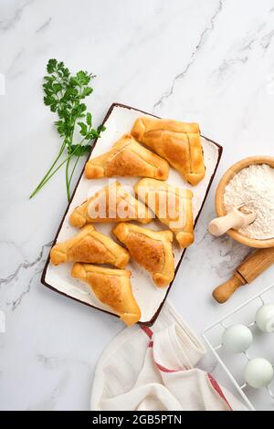 Gebratene Empanadas mit Koriander, Fleisch, Ei, Tomaten und Chilisauce auf weißem Hintergrund. Konzept des lateinamerikanischen und chilenischen Unabhängigkeitstages. Stockfoto