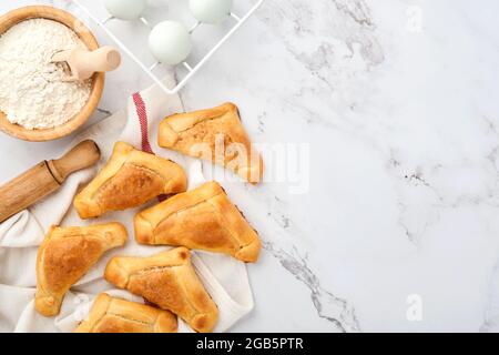 Gebratene Empanadas mit Koriander, Fleisch, Ei, Tomaten und Chilisauce auf weißem Hintergrund. Konzept des lateinamerikanischen und chilenischen Unabhängigkeitstages. Stockfoto