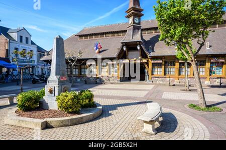 Der Marechal Foch-Platz in Etretat, Frankreich, mit dem Alten Markt, einer überdachten Markthalle aus dem Jahr 1927, und einem Obelisk-förmigen Brunnen an einem sonnigen Morgen. Stockfoto