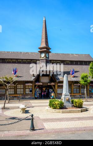Der Marechal Foch-Platz in Etretat, Frankreich, mit dem Alten Markt, einer überdachten Markthalle aus dem Jahr 1927, und einem Obelisk-förmigen Brunnen an einem sonnigen Tag. Stockfoto