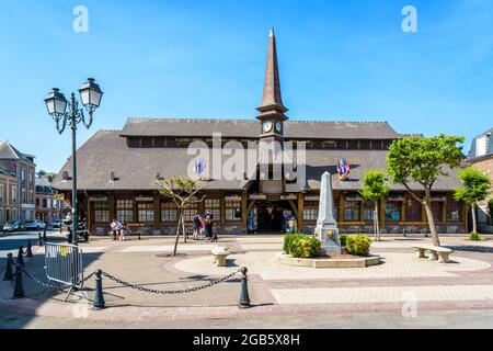 Der Marechal Foch-Platz in Etretat, Frankreich, mit dem Alten Markt, einer überdachten Markthalle aus dem Jahr 1927, und einem Obelisk-förmigen Brunnen an einem sonnigen Tag. Stockfoto