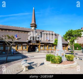 Der Marechal Foch-Platz in Etretat, Frankreich, mit dem Alten Markt, einer überdachten Markthalle aus dem Jahr 1927, und einem Obelisk-förmigen Brunnen an einem sonnigen Morgen. Stockfoto