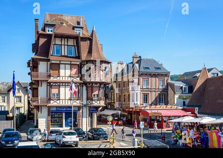 Typische normannische Gebäude auf dem Victor Hugo Platz in Etretat, Frankreich, mit Straßencafés, Restaurant und einem Strandgeschäft an einem sonnigen Tag. Stockfoto