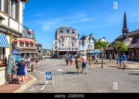 Touristen, die auf dem Marechal Foch Platz in Etretat, Frankreich, flanieren, gesäumt von dem Alten Markt, Fachwerkhäusern, Restaurants, Hotels und Souvenirläden Stockfoto