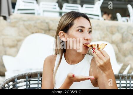 Nahaufnahme des Porträts einer glücklichen asiatischen amerikanerin, die Pizza isst. Stockfoto