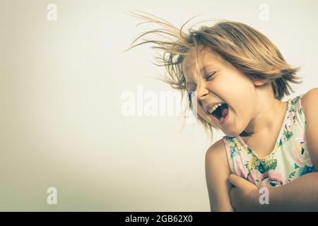 Fröhliches kleines Mädchen lacht sorglos. studioportrait Stockfoto