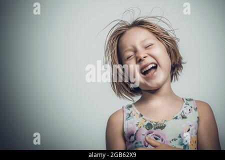 kaukasisches kleines Mädchen mit kurzen Haaren lacht sorglos. studioportrait Stockfoto