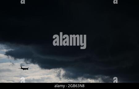 02. August 2021, Hessen, Frankfurt/Main: Unter einer dunklen Wolkenfront nähert sich ein Flugzeug dem Frankfurter Flughafen. Foto: Arne Dedert/dpa Stockfoto