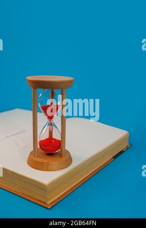 sanduhr und Buch auf blau auf blauem Hintergrund Stockfoto