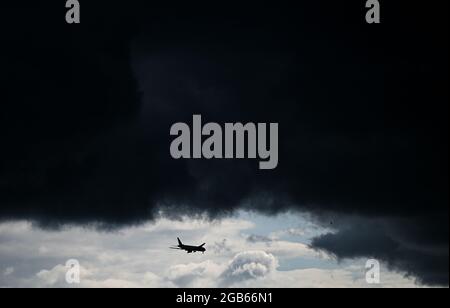 02. August 2021, Hessen, Frankfurt/Main: Unter einer dunklen Wolkenfront nähert sich ein Flugzeug dem Frankfurter Flughafen. Foto: Arne Dedert/dpa Stockfoto