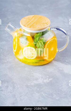 Limonade entgiften Trinken Sie Wasser, Zitrone, Orange und Minze in einer transparenten Teekanone. Eistee-Cocktail mit Limettenminze. Sommergetränk. Speicherplatz kopieren Stockfoto