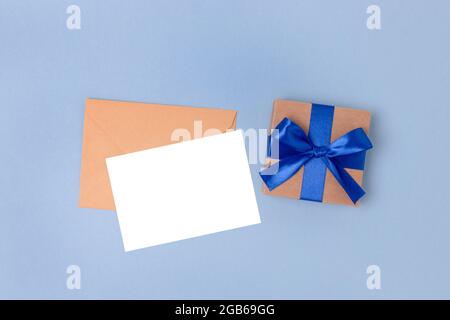 Umschlag, leeres Papierkartenmockup und Geschenkkarton auf blauem Hintergrund. Geschenk und Brief für Vatertag. Stockfoto