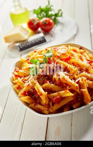 Von oben Schüssel mit leckeren Penne arrabiata von Holztisch neben frischen Zutaten platziert Stockfoto