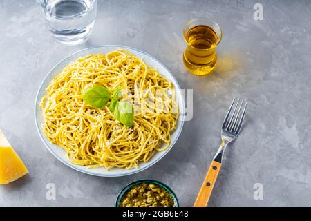 Italienische Pasta mit Saucenpesto und Zutaten. Spaghetti mit Pesto-Sauce und Basilikum auf grauem Hintergrund. Draufsicht Stockfoto