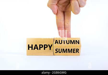 Symbol für den Wechsel von Sommer zu Herbst. Geschäftsmann dreht einen Holzwürfel und ändert die Worte „Happy Summer“ in „Happy Autumn“. Schöner weißer Hintergrund Stockfoto