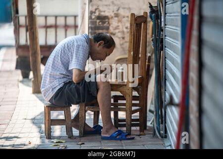 Ein Mann reckt seine Nudeln draußen auf einem provisorischen Tisch in einem Dorf in China Stockfoto