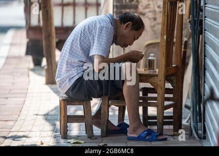 Ein Mann reckt seine Nudeln draußen auf einem provisorischen Tisch in einem Dorf in China Stockfoto